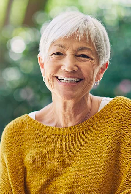 Mature woman in a yellow sweater smiling