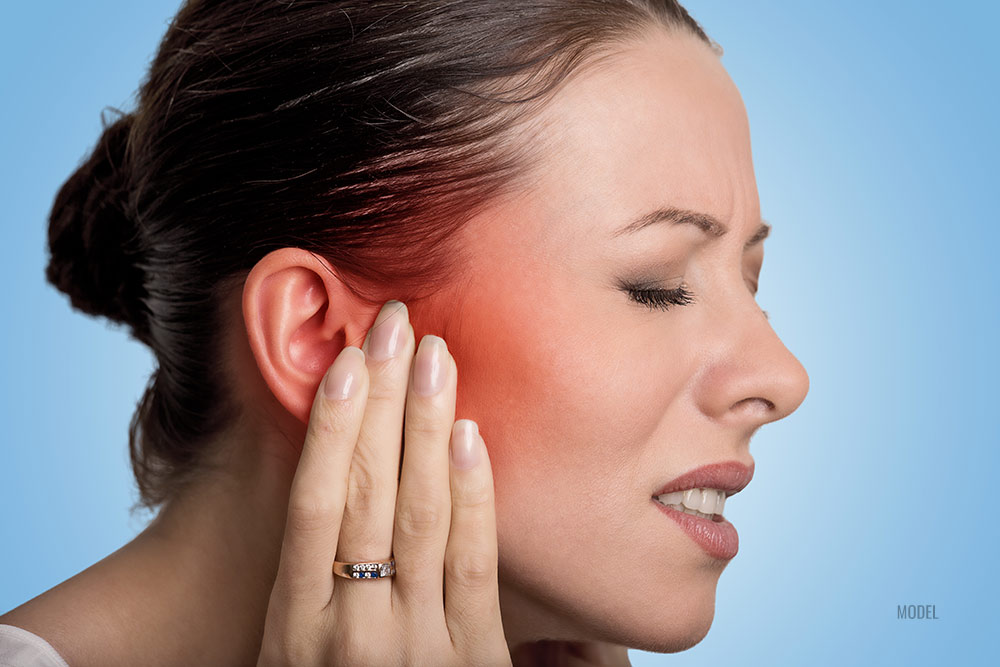 Women holding her ear because of dental pain